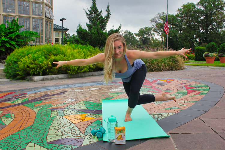 Woman performing a yoga pose standing on one leg with outstretched arms.  True lemon 