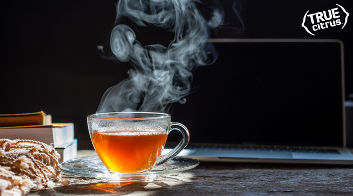 Cup of hot tea with steam rising from it in a glass mug.