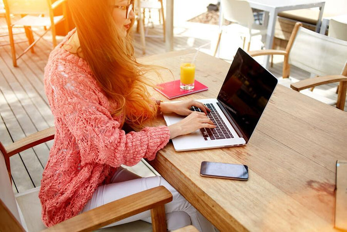 women works on her laptop while drinking juice