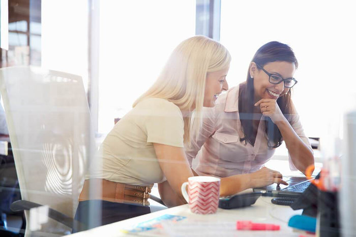 two women laughing while at work