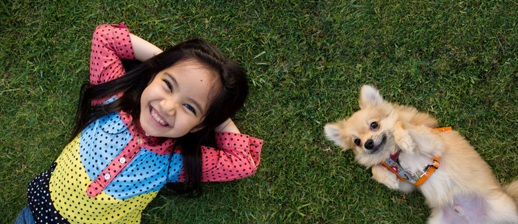 girl with bright colored shirt lying on grace with dog