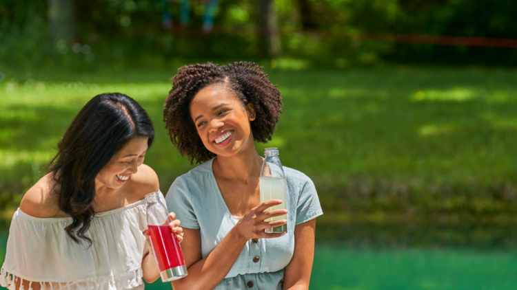 Two best friends sitting together outside drinking True Lemon Lemonade. 