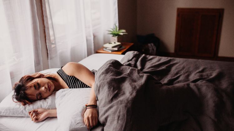 A woman sleeping soundly in her bed as the sun beings to rise.