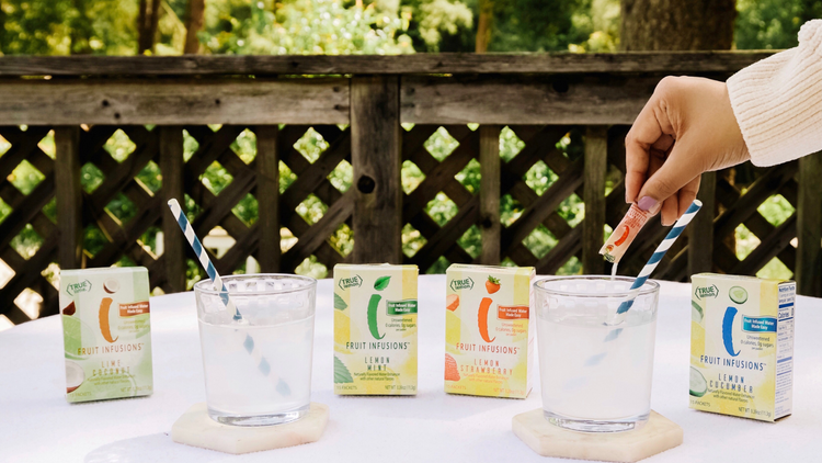 A woman pouring a packet of True Lemon Fruit Infusions into a glass. True Lemon Fruit Infusions are the easiest fruit infused water.