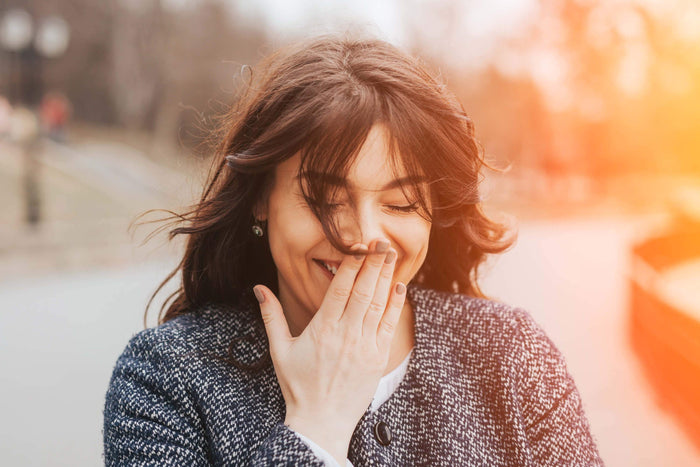 women laughs with her hand over her mouth