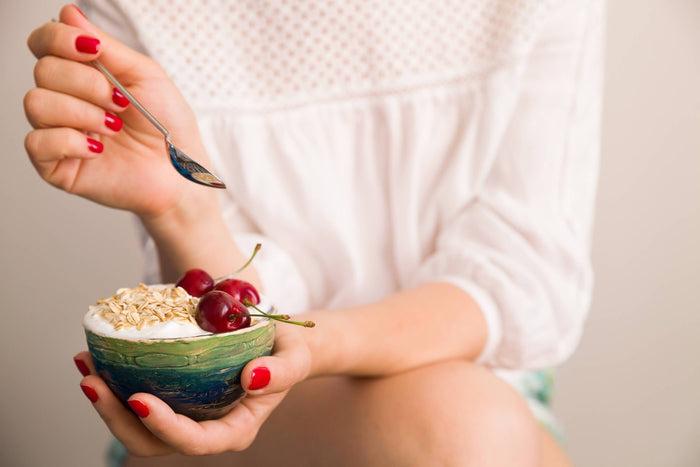 women eats a bowl of yogurt cherries and oats