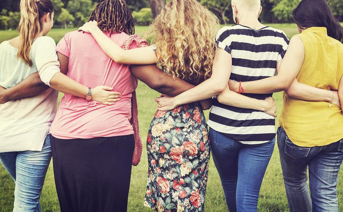 three women embracing while walking away from camera