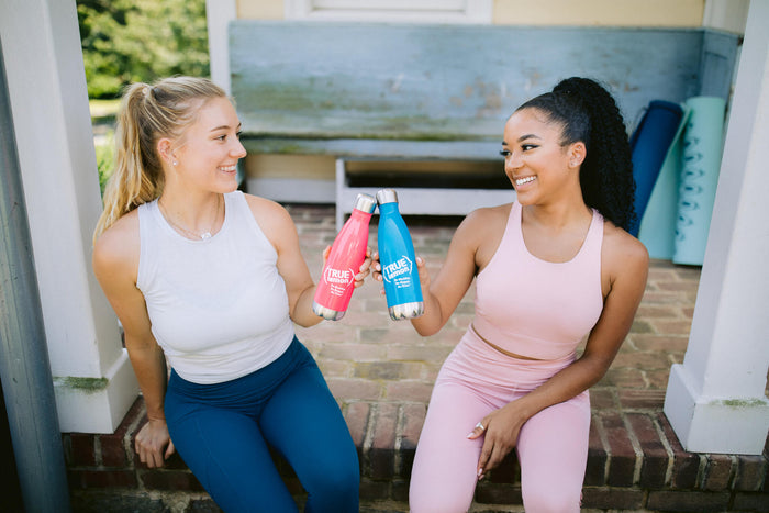 two-women-post-workout-toasting-with-reusable-insulated-water-bottles-going-green-take-care-of-mother-earth-day