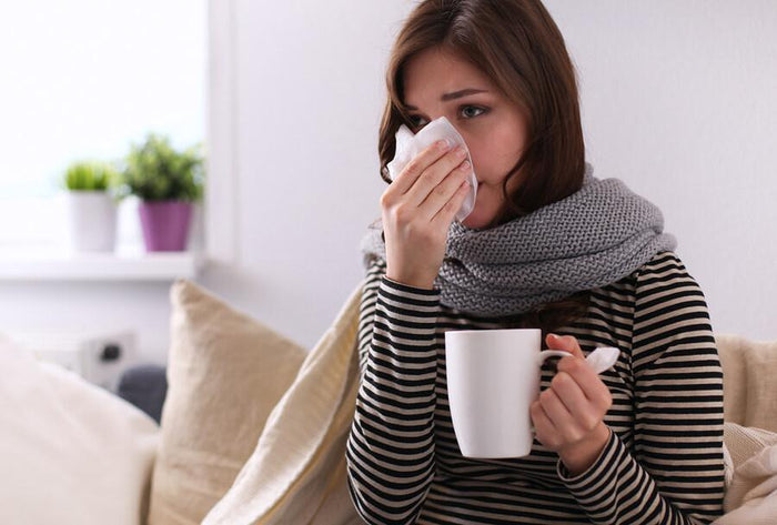 women sneezes and drinks tea