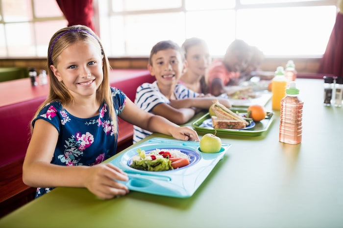 School children eating snacks at school smiling at the camera