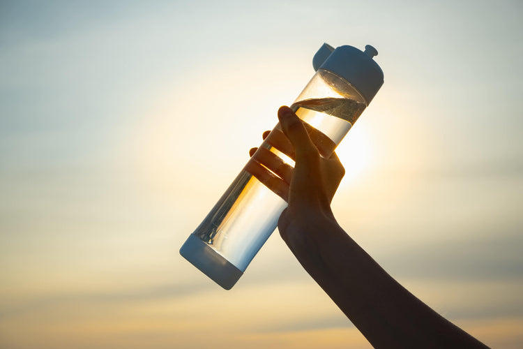 hand-holding-water-bottle-in-sunlight-summer-hydration-summertime