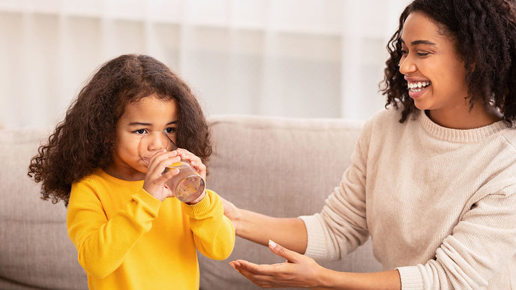 mother smiles as she watches her daughter drink a glass of True Lemon lemonade