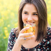 A woman happily enjoys a glass of True Lemon Iced Tea outside. 